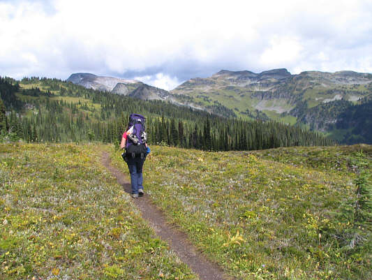 The trail eventually winds its way over to the distant green slopes at far right.